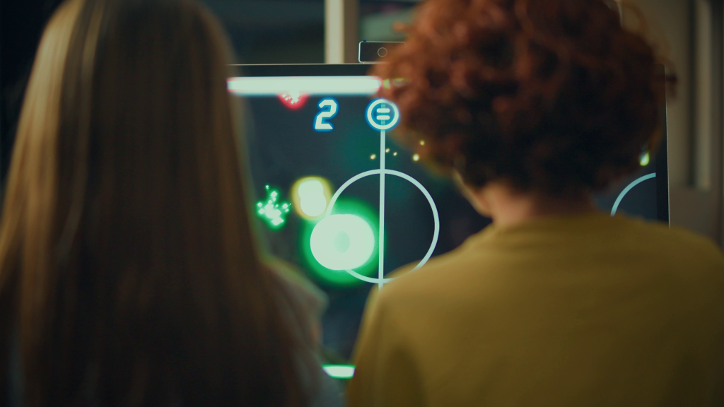 Niños jugando Air Hockey digital en pantalla táctil OneScreen Wandr 32 pulgadas.